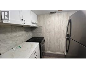 A kitchen with a refrigerator, stove, and cabinets.