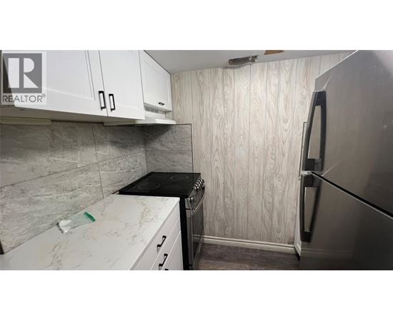 A kitchen with a refrigerator, stove, and cabinets.