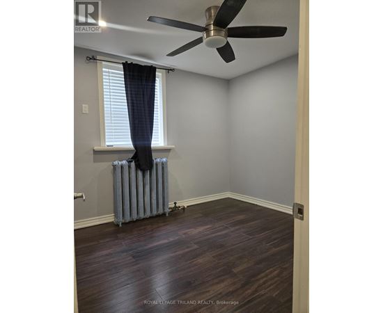 A room with a ceiling fan and a radiator on the floor.