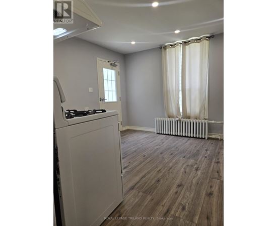 A kitchen with a white stove top oven and a window with white curtains.