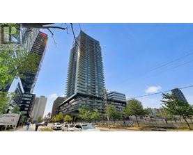 A modern glass building stands tall in a cityscape with other buildings and trees around it.