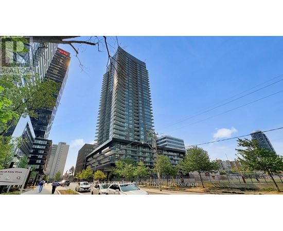 A modern glass building stands tall in a cityscape with other buildings and trees around it.