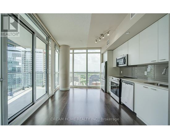 A modern kitchen with white cabinets and a view of the city.