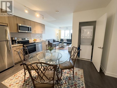 A kitchen with a glass table and chairs in the foreground and a refrigerator, microwave, oven, and sink in the background.