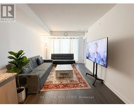 A living room with a grey couch, a coffee table, and a flat screen TV.