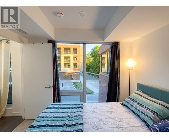 A bedroom with a bed and a window overlooking a street.