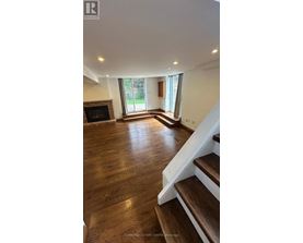 A living room with a fireplace and wooden floors.
