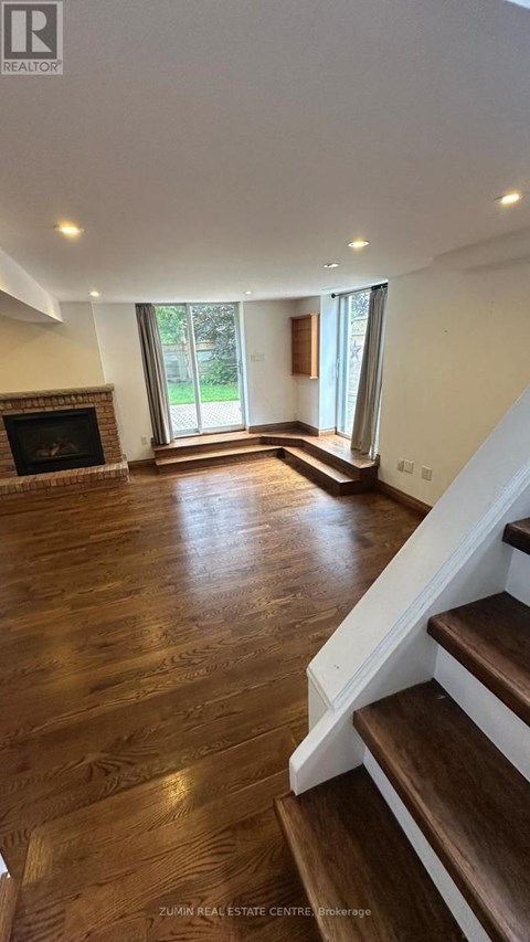 A living room with a fireplace and wooden floors.