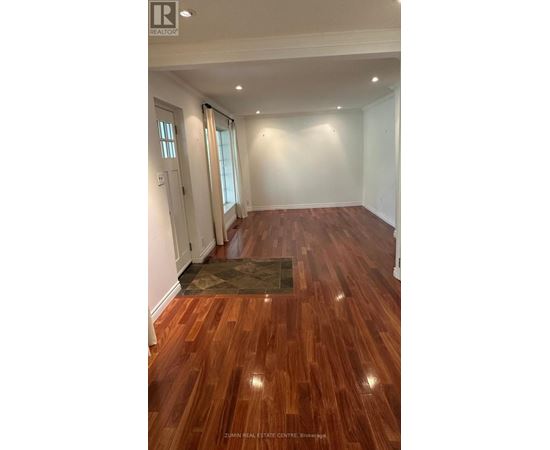A room with wooden flooring and a rug in the middle.
