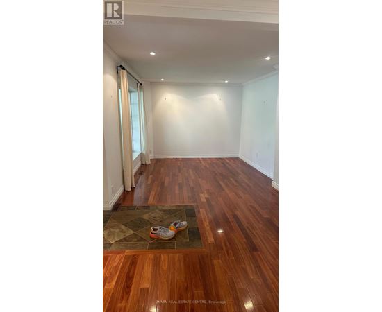 A room with wooden floors and a rug with shoes on it.