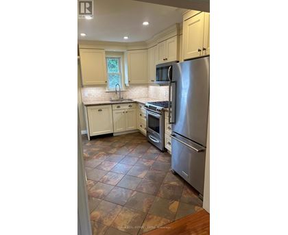 A kitchen with a refrigerator, oven, and sink.