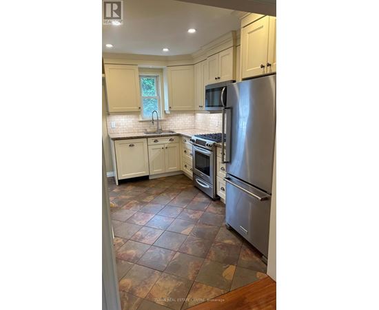 A kitchen with a refrigerator, oven, and sink.