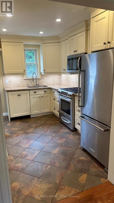 A kitchen with a refrigerator, oven, and sink.