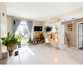 A living room with a white chair, a wooden table, and a television.