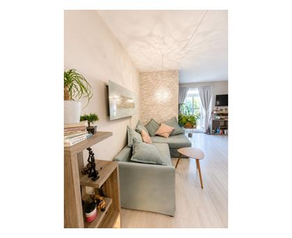 A living room with a grey couch and a wooden shelf.