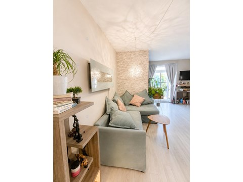 A living room with a grey couch and a wooden shelf.