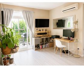 A room with a desk, chair, and a television.