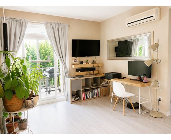 A room with a desk, chair, and a television.