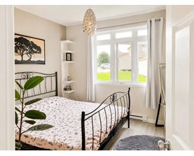 A bedroom with a large bed and a painting of a tree on the wall.