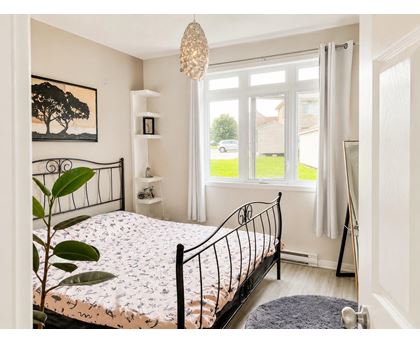 A bedroom with a large bed and a painting of a tree on the wall.