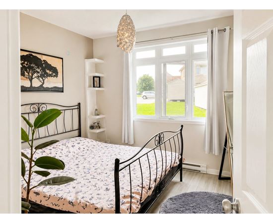 A bedroom with a large bed and a painting of a tree on the wall.