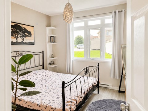 A bedroom with a large bed and a painting of a tree on the wall.