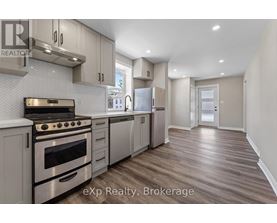 A modern kitchen with stainless steel appliances and wooden flooring.