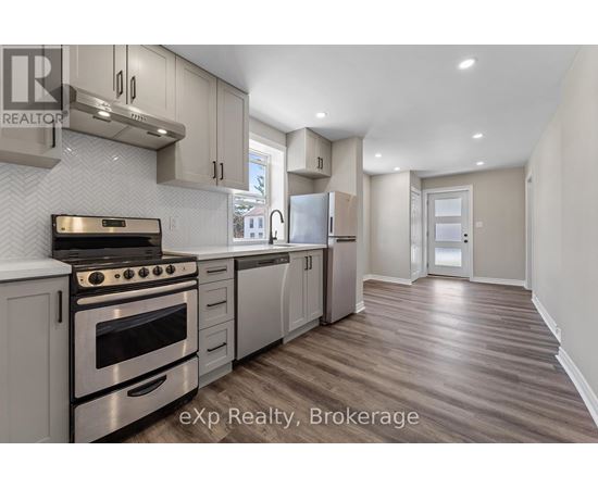 A modern kitchen with stainless steel appliances and wooden flooring.