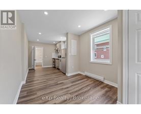 A well-lit, empty room with wooden flooring and white walls.