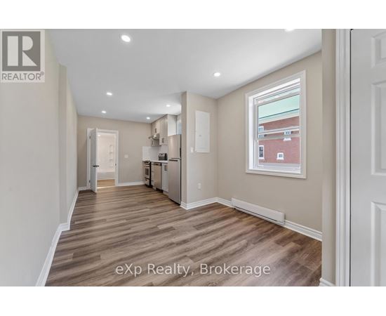 A well-lit, empty room with wooden flooring and white walls.