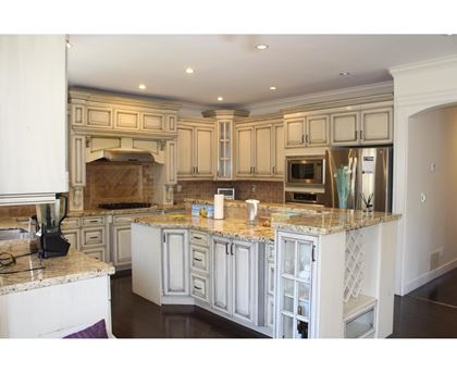 A kitchen with a marble countertop and white cabinets.