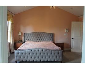 A bedroom with a large bed and a chandelier.