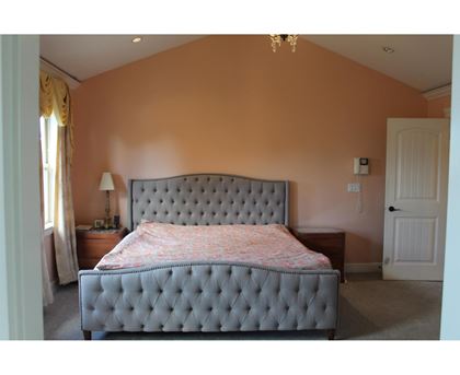 A bedroom with a large bed and a chandelier.