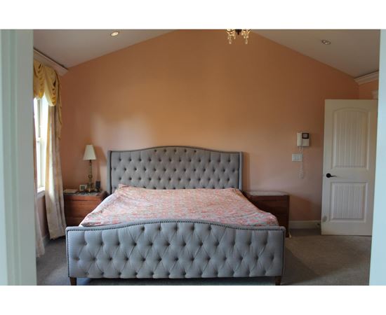 A bedroom with a large bed and a chandelier.