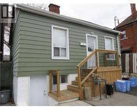 A green house with a wooden deck and a small porch.