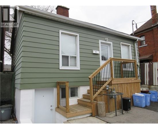 A green house with a wooden deck and a small porch.