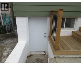 A white door is on the left of a wooden porch.