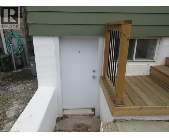 A white door is on the left of a wooden porch.