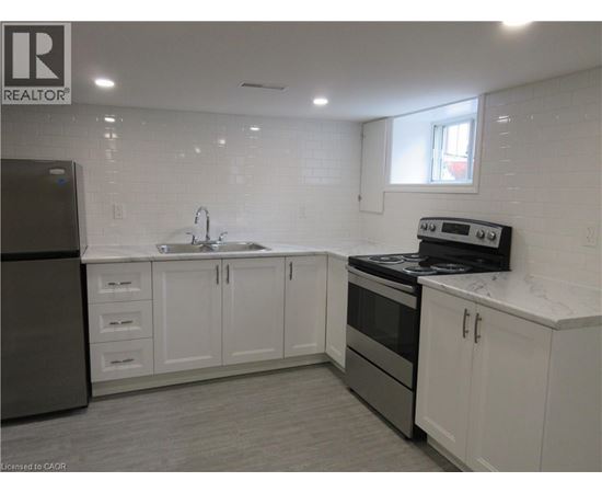 A kitchen with white cabinets and a black refrigerator.