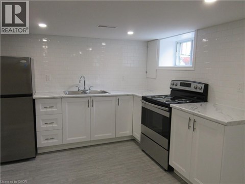 A kitchen with white cabinets and a black refrigerator.