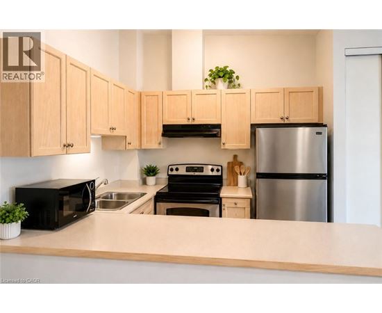A kitchen with wooden cabinets and a stainless steel refrigerator.
