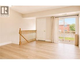 A room with a wooden staircase and sliding glass doors.