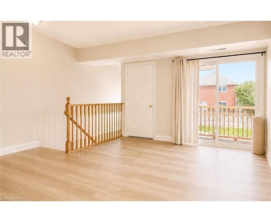 A room with a wooden staircase and sliding glass doors.