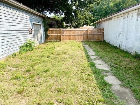 A backyard with a wooden fence and a concrete path.