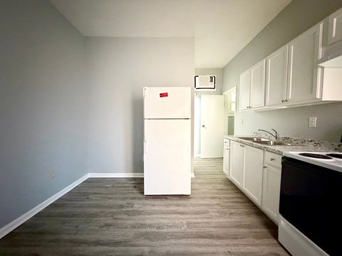 A white refrigerator in a kitchen with wooden floors.