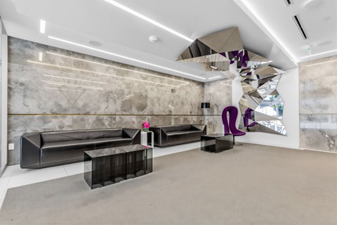 A modern living room with a grey sofa and a grey rug.