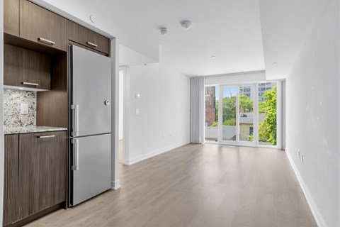 A kitchen with a refrigerator and wooden cabinets.