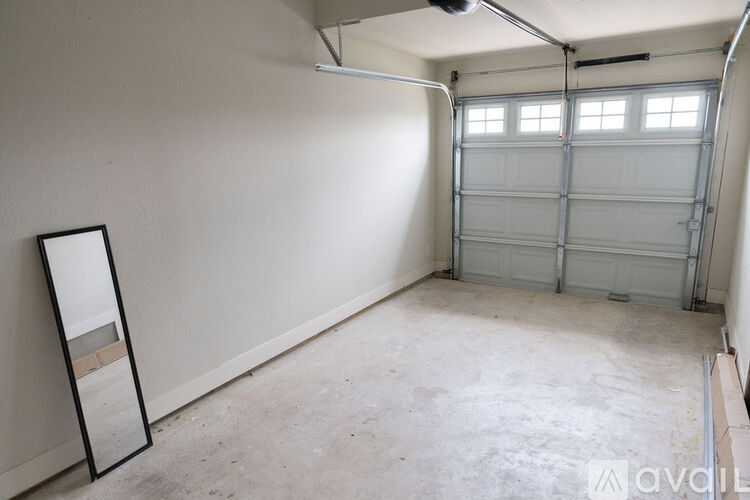 A spacious garage with a white wall and a large mirror on the left side.