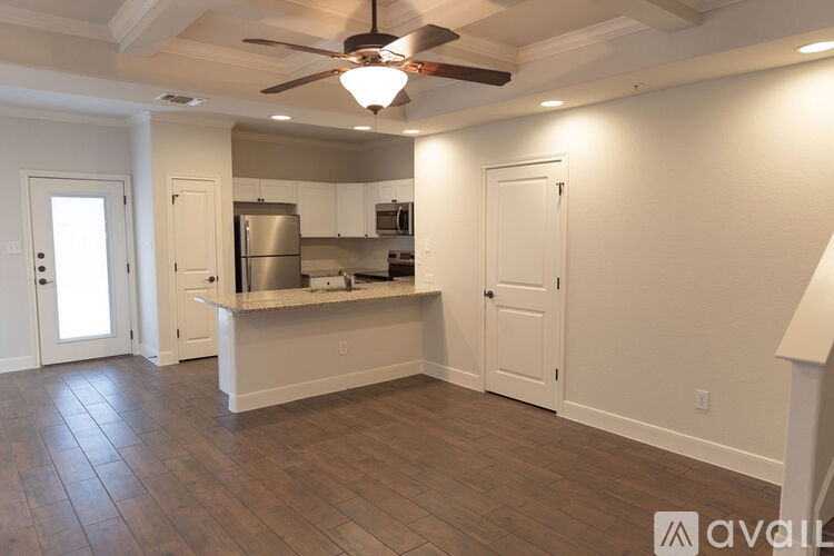 A kitchen with white cabinets and a wooden floor.