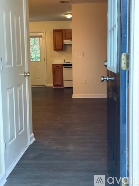 A hallway with a blue door and a white door on the left.